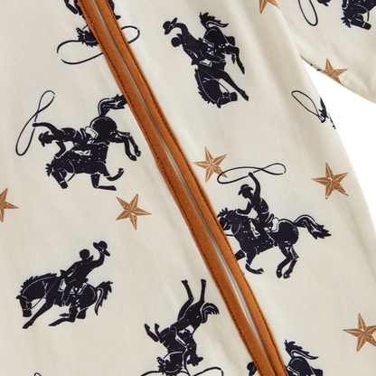 Close-up detail of the smooth diagonal zipper running across the chest, highlighting the lone star, horse, and lasso cowboy print on the baby boy jumpsuit.