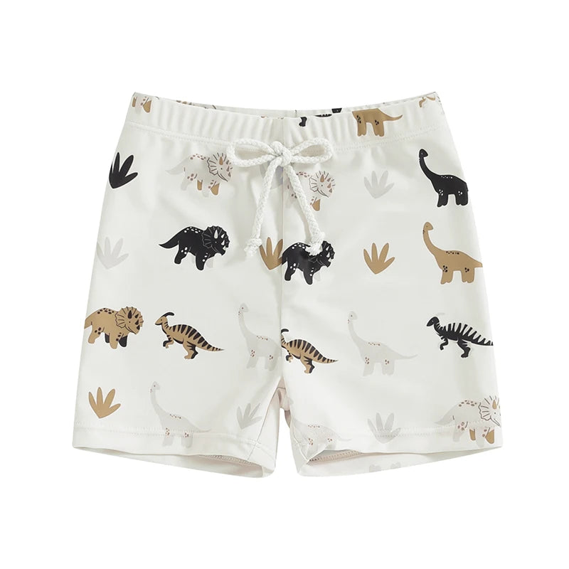 Toddler boys ivory swim shorts with a modern earth-tone dinosaur pattern including black, tan, and charcoal silhouettes and stylized plant icons.