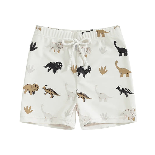 Toddler boys ivory swim shorts with a modern earth-tone dinosaur pattern including black, tan, and charcoal silhouettes and stylized plant icons.