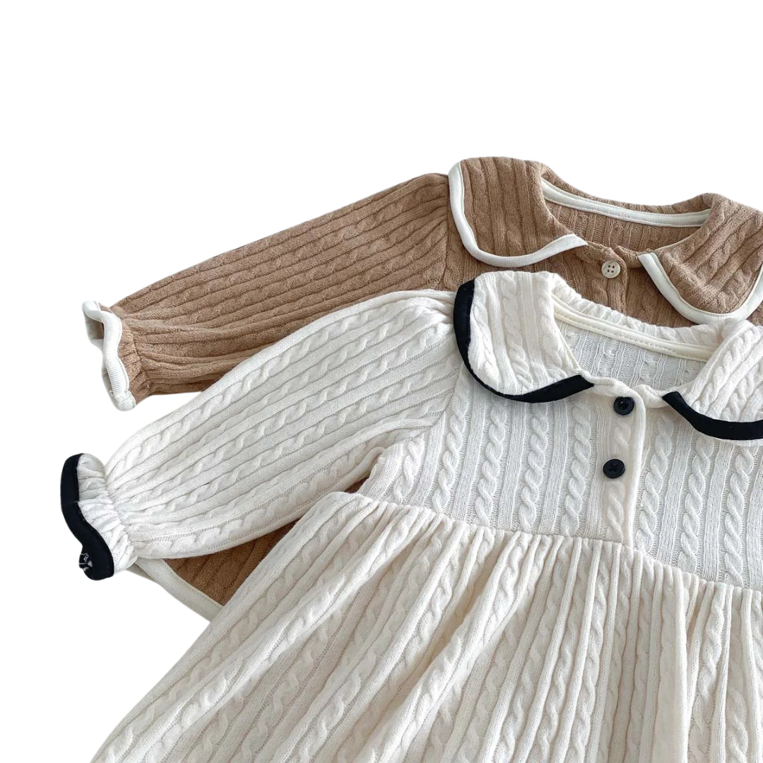 Close up flat lay showing the soft, textured cable knit fabric of both the ivory and chestnut baby dresses.