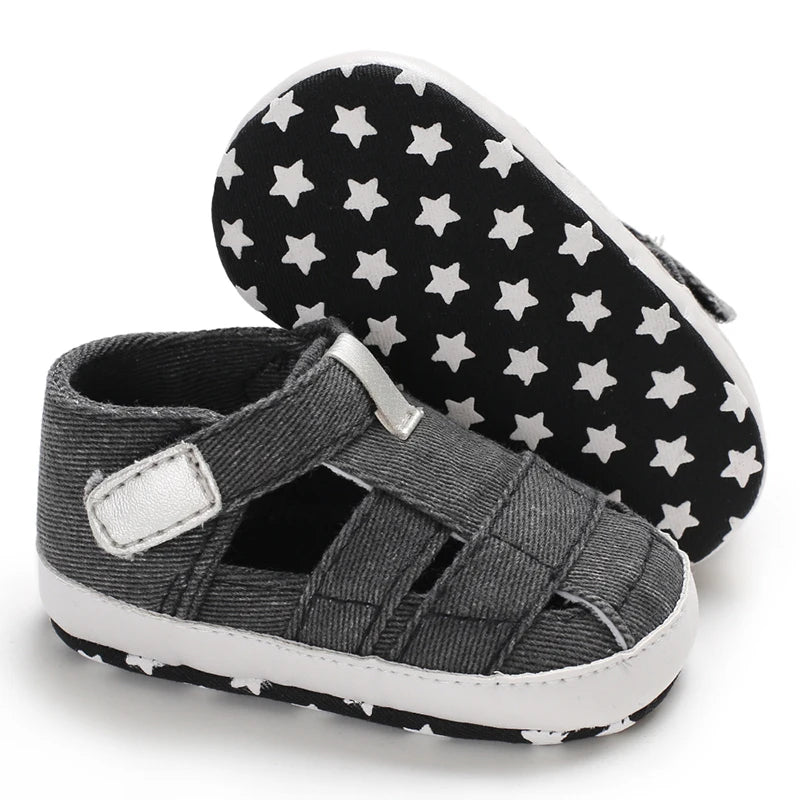 The bottom of a dark gray black baby canvas sandal showing the flexible anti-slip sole with a white star grip pattern.