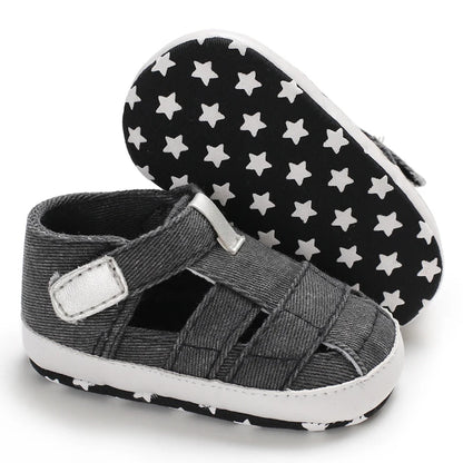 The bottom of a dark gray black baby canvas sandal showing the flexible anti-slip sole with a white star grip pattern.
