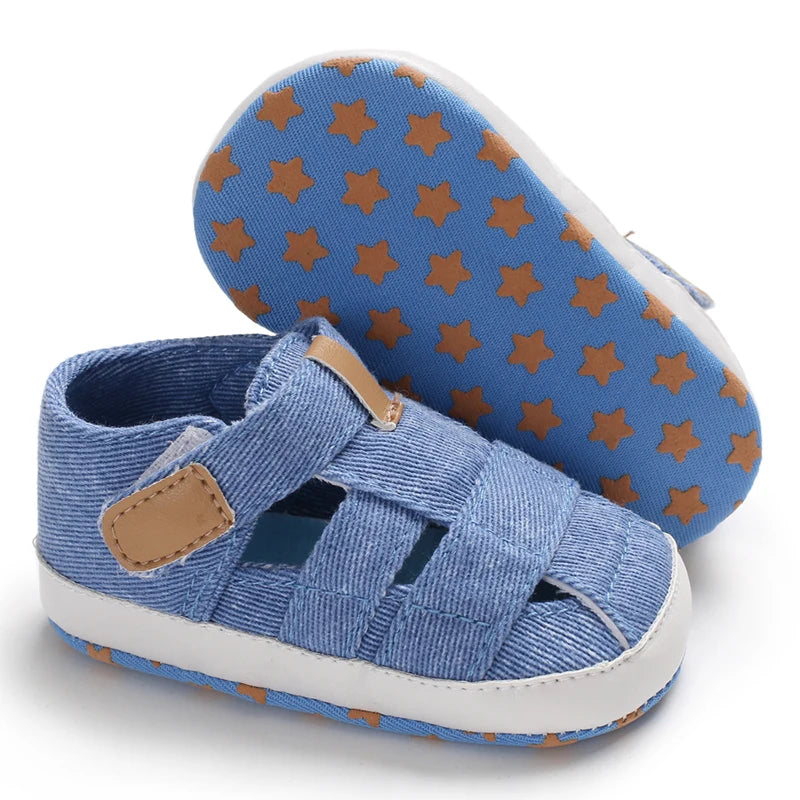 The bottom of a blue baby canvas sandal showing the flexible anti-slip sole with a brown star grip pattern.