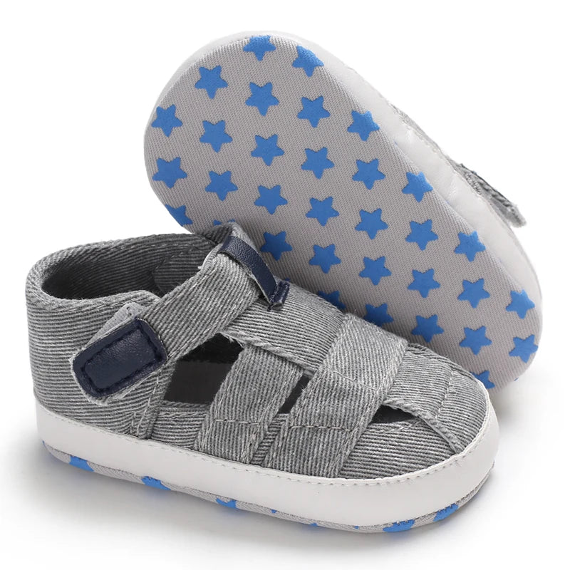 The bottom of a light gray baby canvas sandal showing the flexible anti-slip sole with a blue star grip pattern.