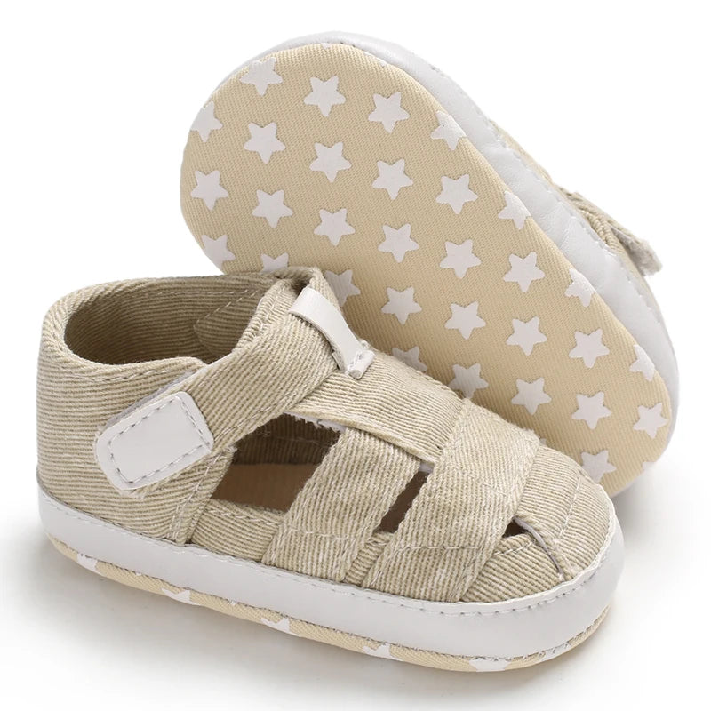 The bottom of a tan baby canvas sandal showing the flexible anti-slip sole with a white star grip pattern.