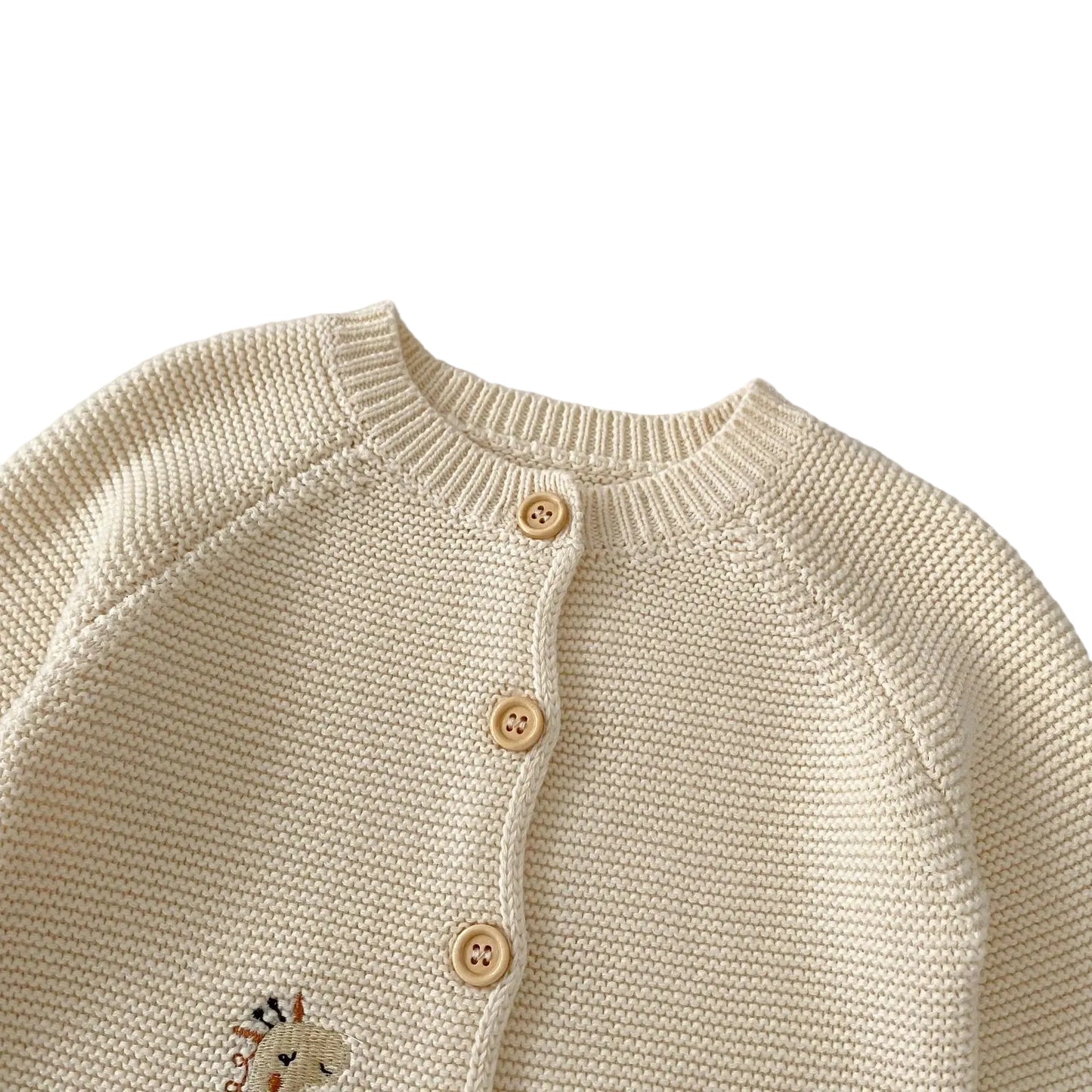 Close-up of the round crewneck neckline and top wooden buttons of the cream cotton baby knit cardigan sweater.