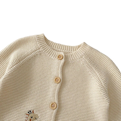 Close-up of the round crewneck neckline and top wooden buttons of the cream cotton baby knit cardigan sweater.