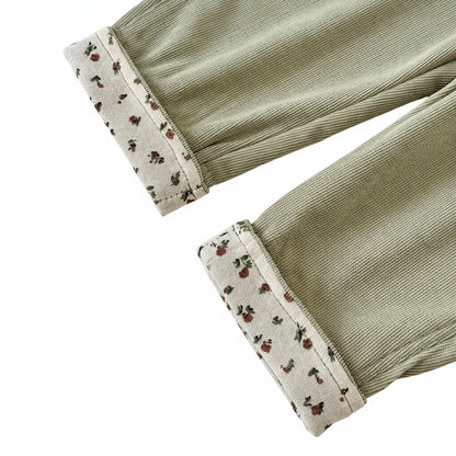 Close-up detail of the adjustable rolled floral-print cuffed hems on sage green baby corduroy overalls.