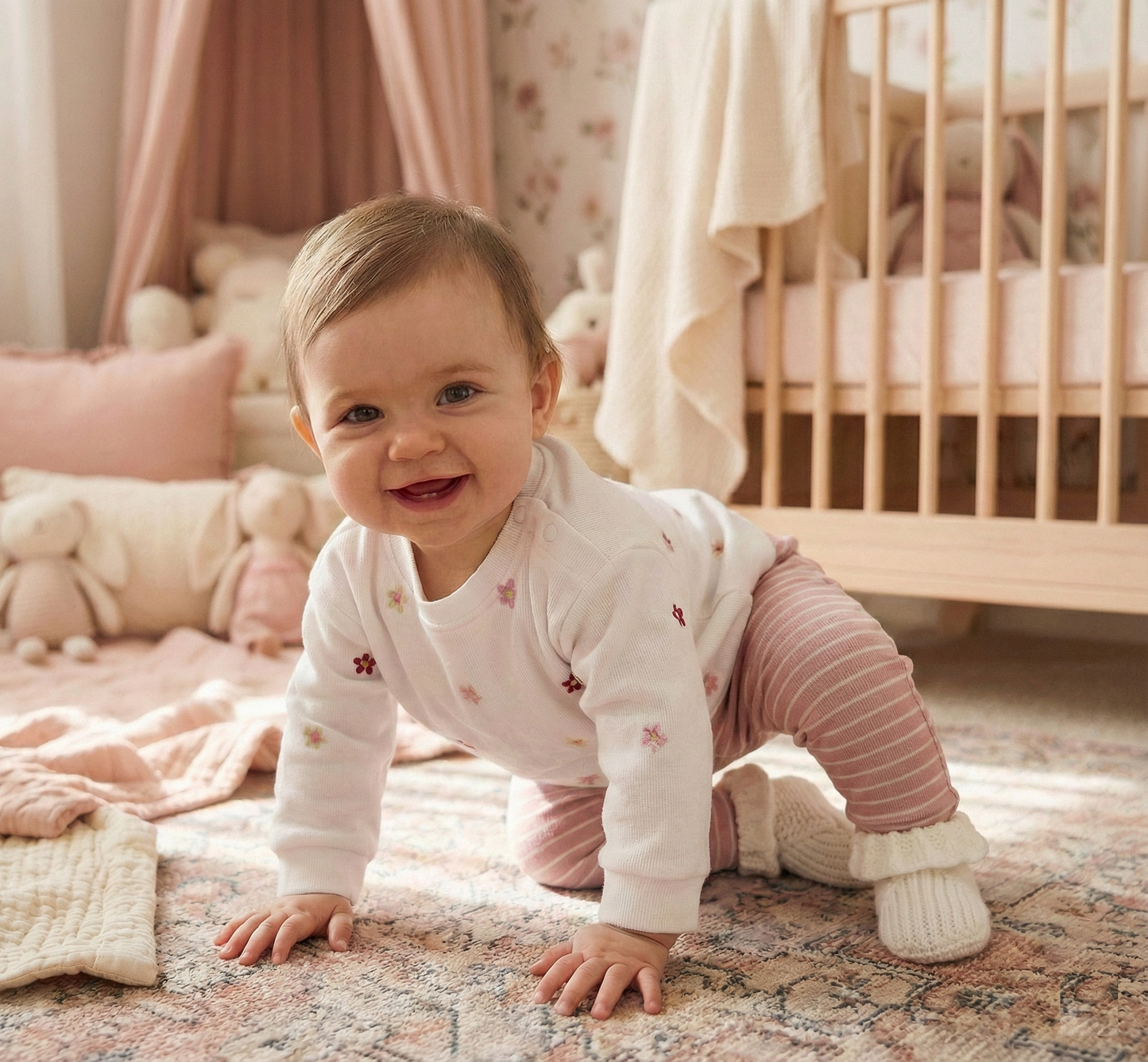 Happy baby girl crawling on a rug in a beautifully decorated nursery room wearing the white floral sweatshirt and pink striped leggings outfit.