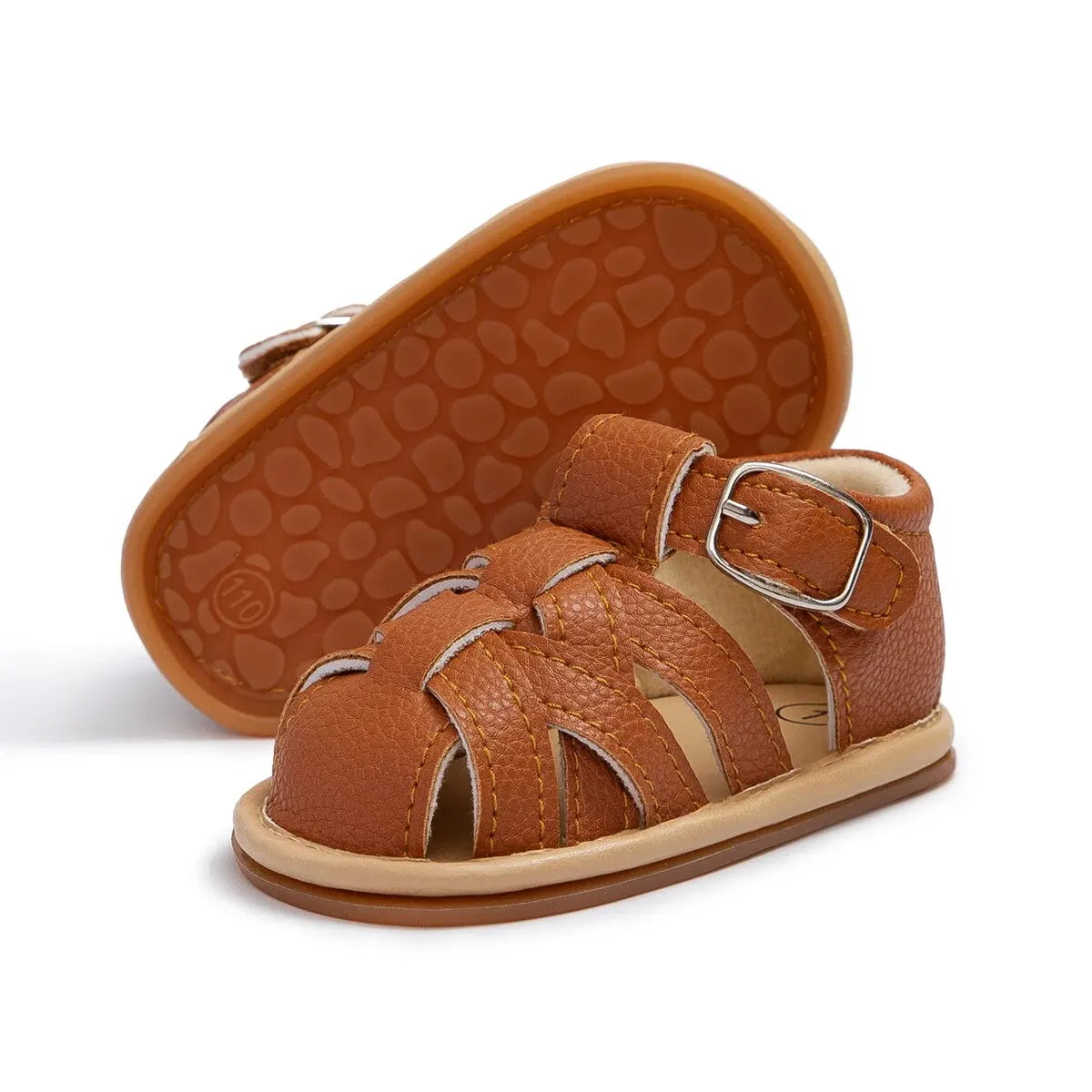Brown infant fisherman sandal next to an upturned shoe showing its flexible textured rubber anti-slip sole.