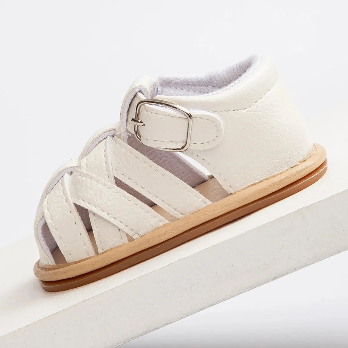 Clean side profile view of a white baby fisherman sandal showing the precision stitching and covered heel design.