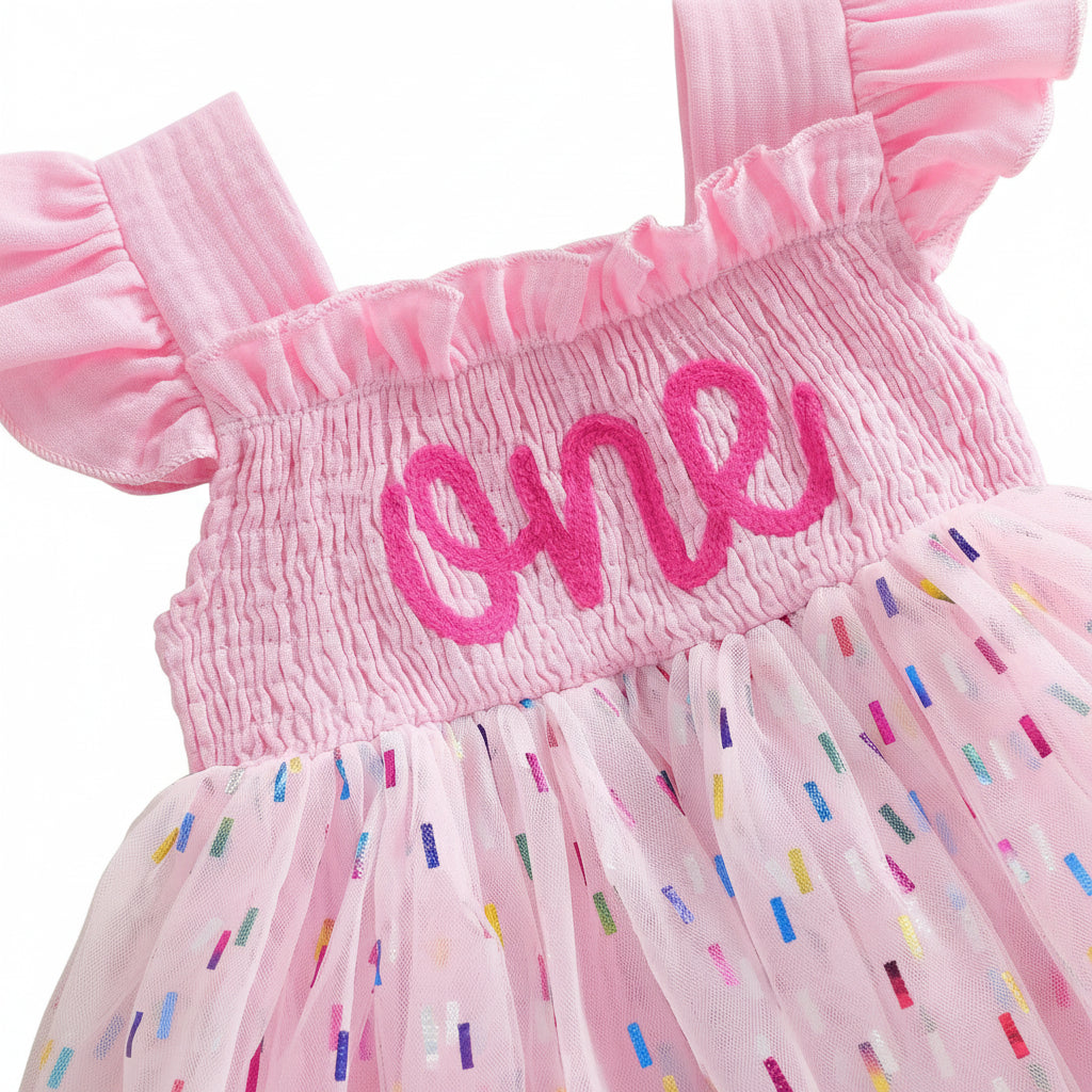 Close up of the stretchy smocked bodice and "one" embroidery on the pink 1st birthday tutu romper.