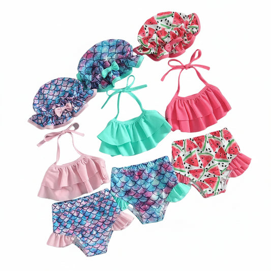 Three-piece baby girl bikini collection featuring pink watermelon print and aqua mermaid scale patterns with matching swim caps.