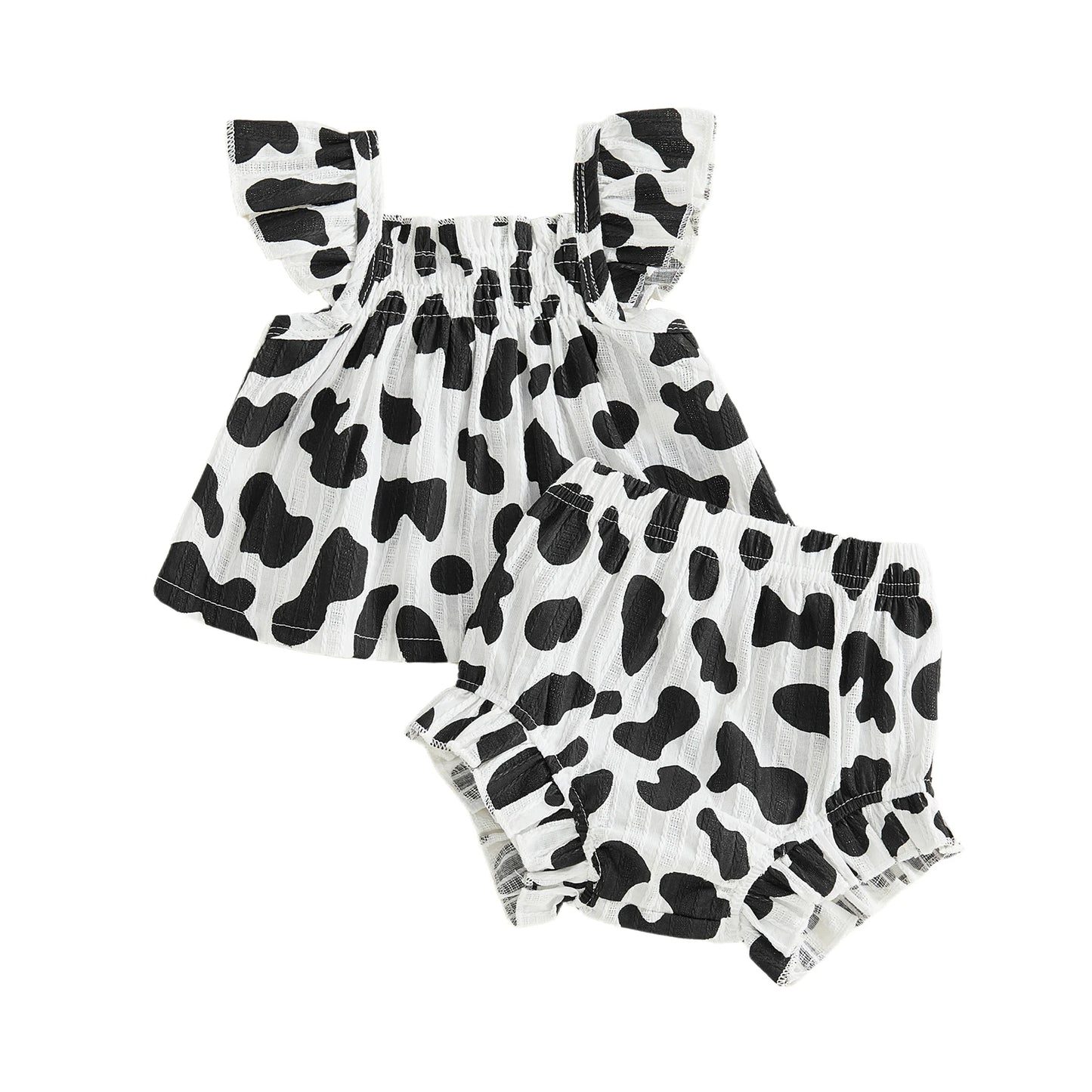 Isolated flat lay of the black and white cow print baby girl two-piece summer set showing the top and shorts.