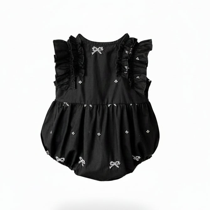 Back view of a black and white baby girl bubble romper showing the cross back straps and ruffle details.