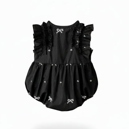 Back view of a black and white baby girl bubble romper showing the cross back straps and ruffle details.