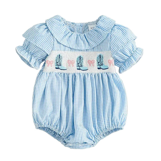Front view of baby girl blue gingham bubble romper featuring a smocked chest with embroidered cowgirl boots and pink bows.