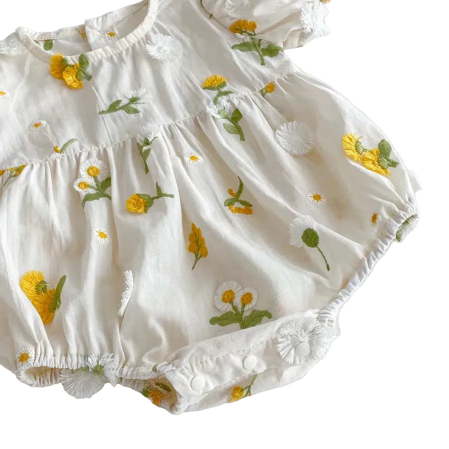 Angled view of the gathered bubble waist and elastic leg openings on a baby girl's white floral summer outfit.