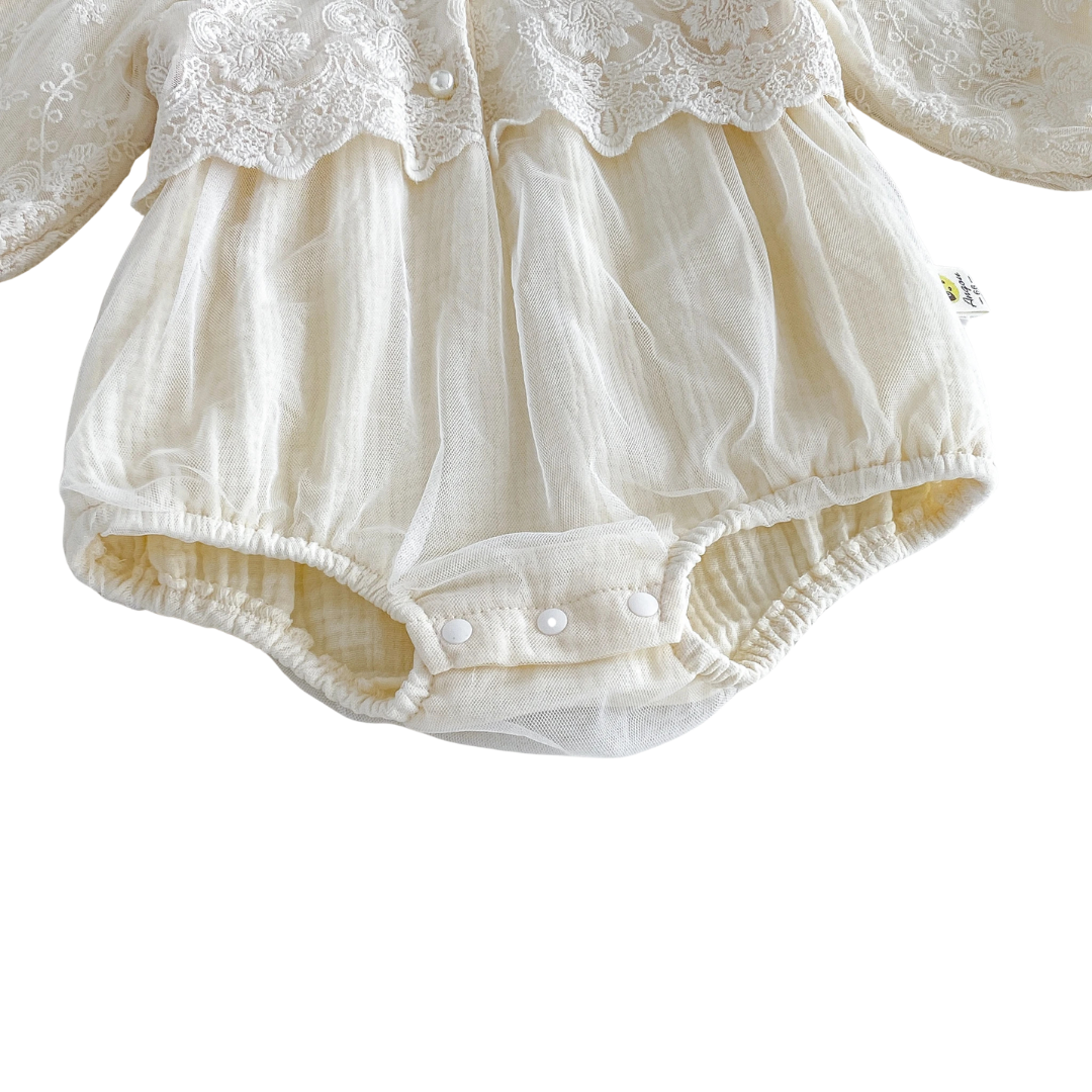 Close-up of gathered elastic legs and 3-snap bottom diaper closure on an ivory cotton-lined baby bubble romper.