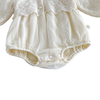 Close-up of gathered elastic legs and 3-snap bottom diaper closure on an ivory cotton-lined baby bubble romper.