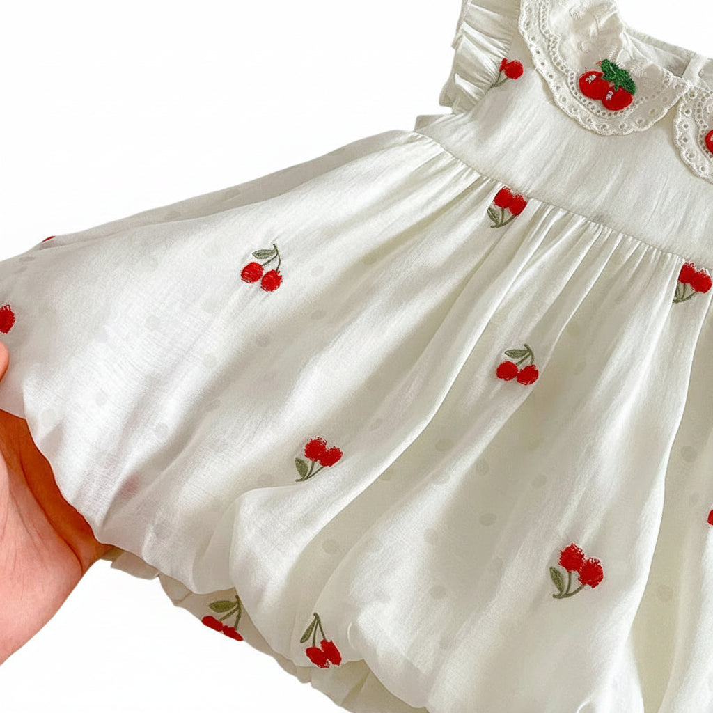 Close-up of the voluminous bubble hem and cherry sprig embroidery on a cotton muslin toddler dress.
