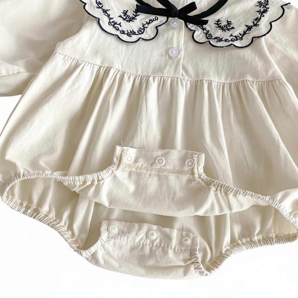 Open view of the bottom diaper area showing the reinforced snap closures on the ivory cotton romper.