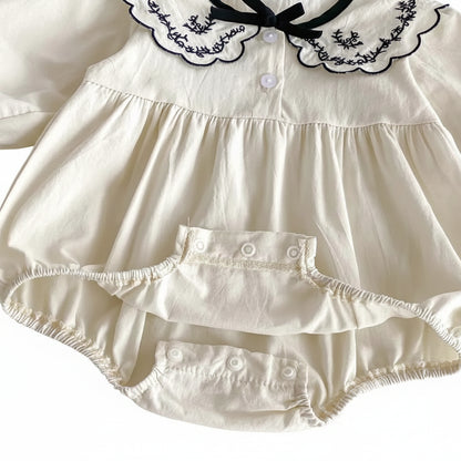 Open view of the bottom diaper area showing the reinforced snap closures on the ivory cotton romper.