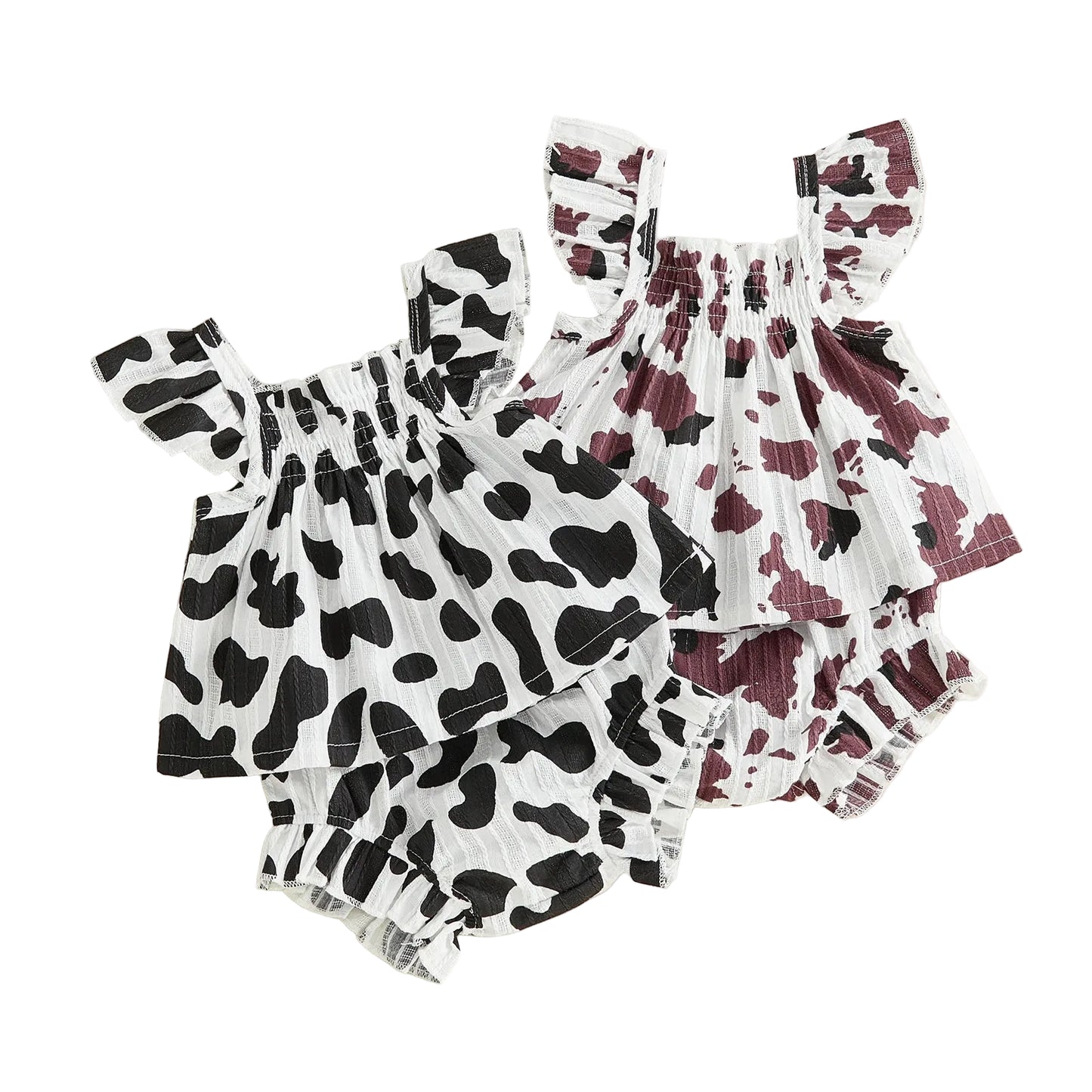 tudio shot displaying two baby girl summer outfits featuring black and white, and brown and white cow prints with smocked ruffled tops and matching shorts.