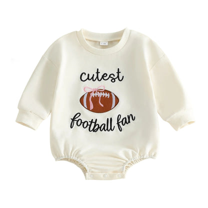 Cream Baby Girl "Cutest Football Fan" Long Sleeve Bubble Romper featuring an embroidered football with a pink bow on a white background.