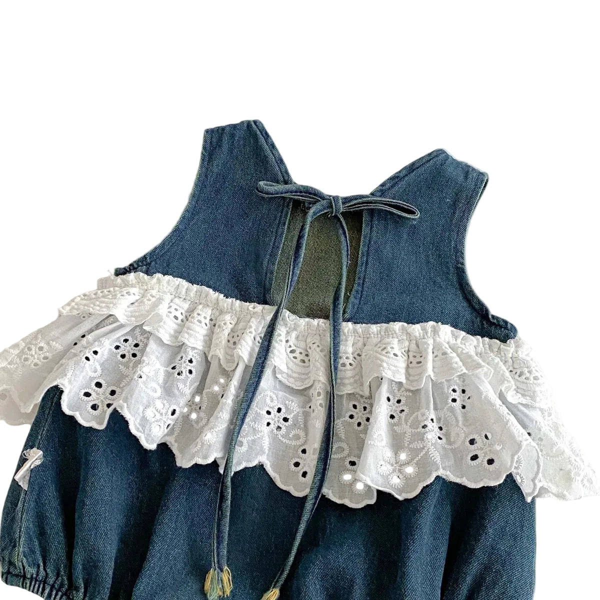The back of a sleeveless baby girl denim romper showing the adjustable functional tie-back closure and ruffled lace trim.
