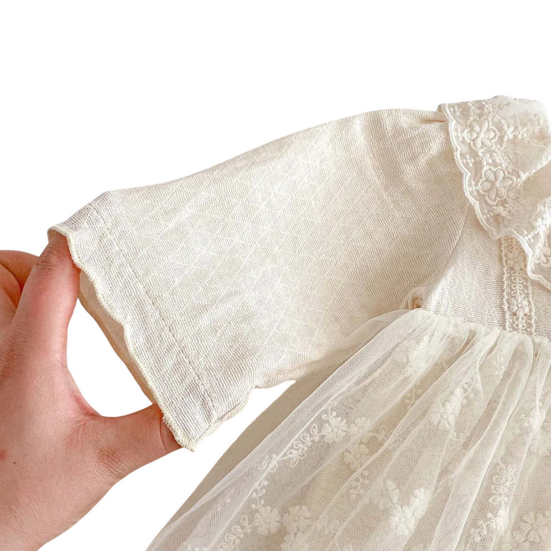 Close-up of the long sleeve on the baby girl dress showing the subtle diamond pique texture of the cotton fabric.