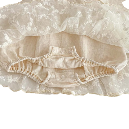 Close-up detail of the three bottom snap closures on the inner bodysuit of the baby girl romper dress for easy diaper changes.