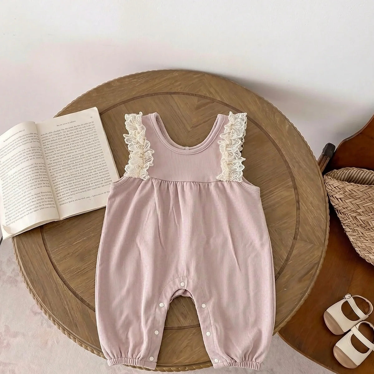 Dusty pink ribbed suspender romper with white lace ruffles along the straps and bottom snap closures
