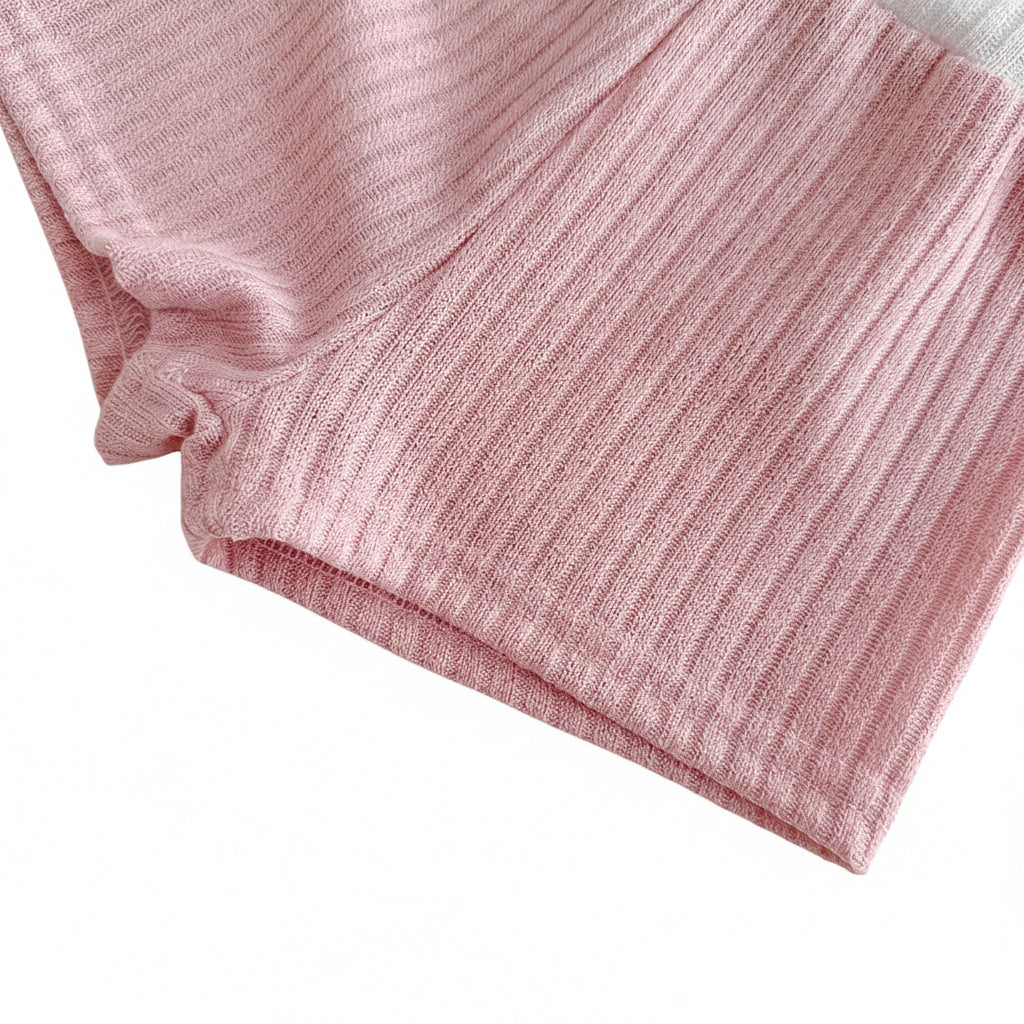 Close-up shot of the hemline and leg opening of the baby girl dusty rose ribbed knit shorts against a white background.
