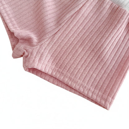 Close-up shot of the hemline and leg opening of the baby girl dusty rose ribbed knit shorts against a white background.