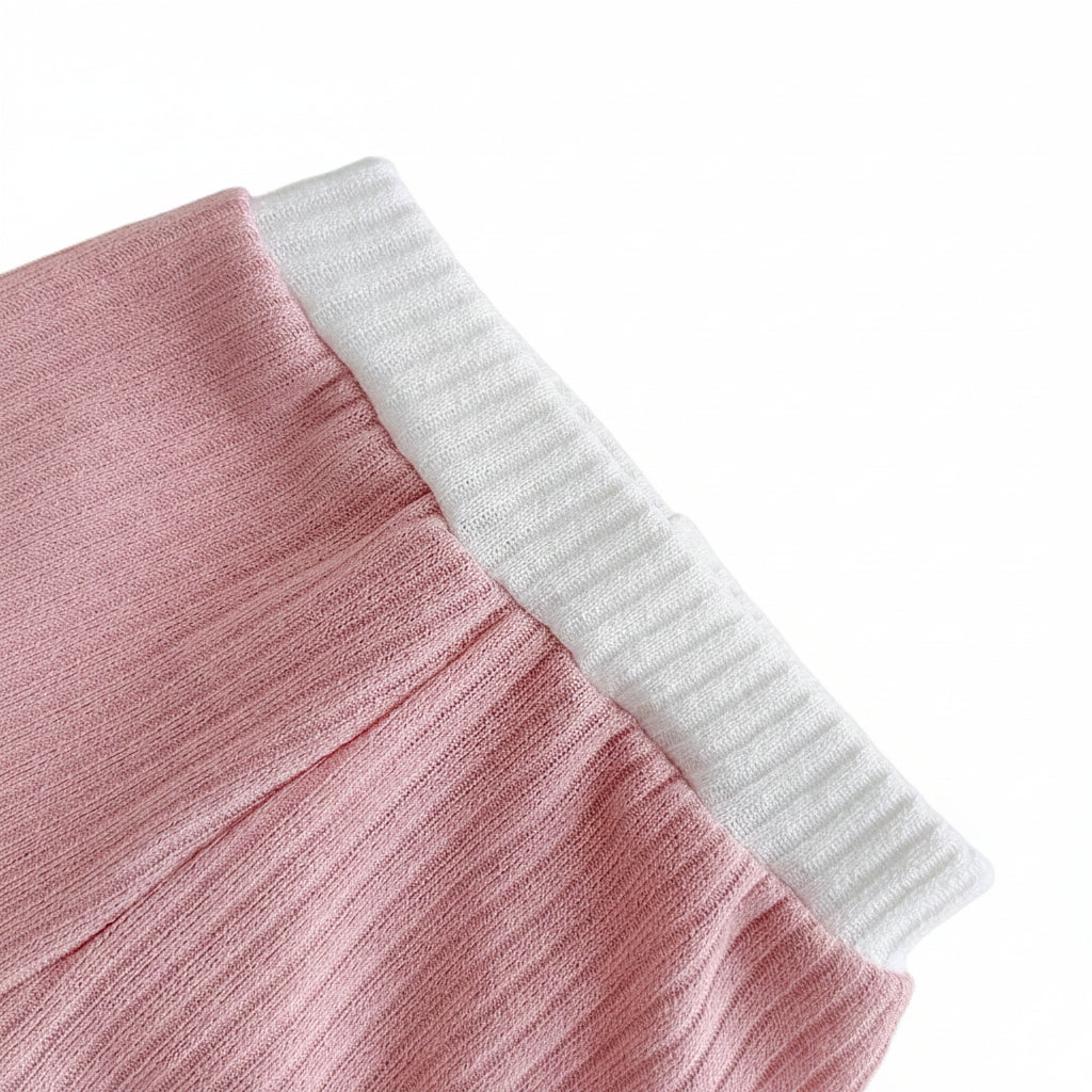 Close-up detail of the easy-on elastic waistband on the dusty rose ribbed knit baby shorts with white contrast trim detailing.