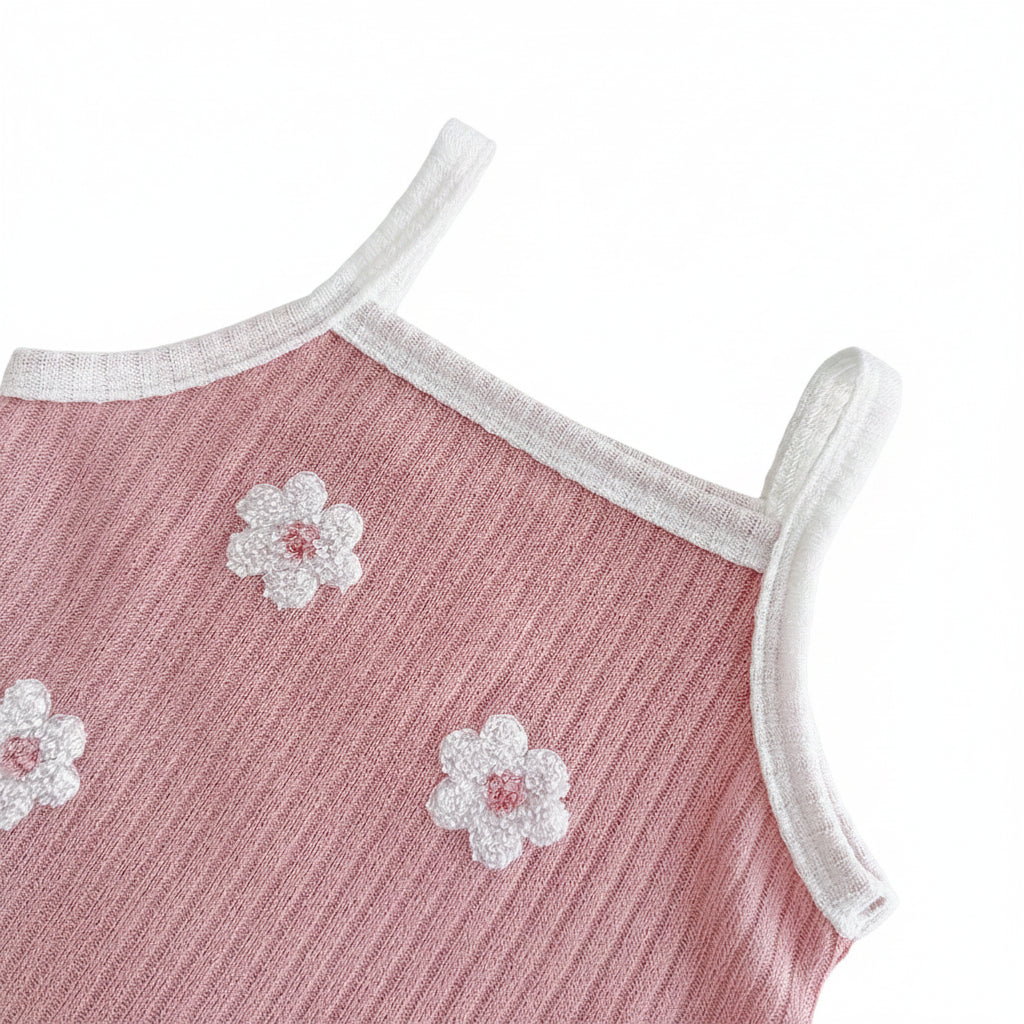 Close-up of the scoop neckline and shoulder strap on the dusty rose ribbed knit tank top, showing a white contrast trim and textured 3D floral appliqués.