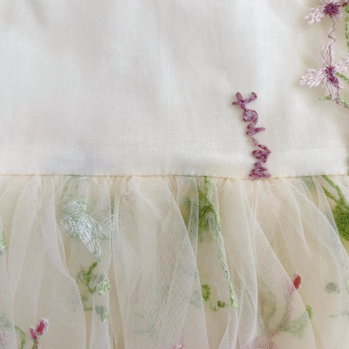 Close up of embroidered flowers on ivory tulle fairy baby dress.