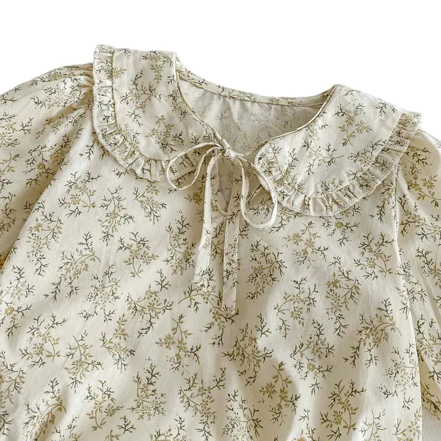 Close-up detail of the ruffled Peter Pan collar, delicate neck tie, and sage wildflower pattern on the Kidsely baby girl romper.