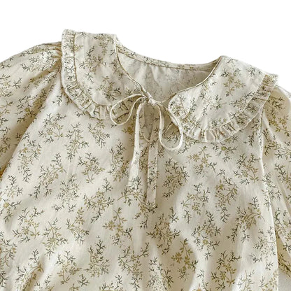 Close-up detail of the ruffled Peter Pan collar, delicate neck tie, and sage wildflower pattern on the Kidsely baby girl romper.