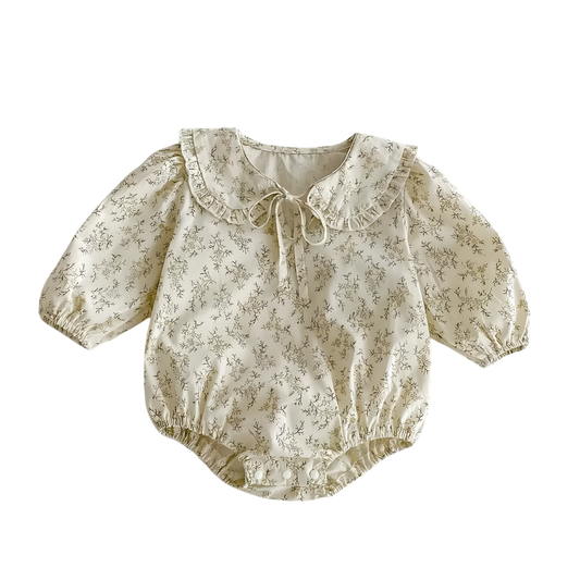 Flat lay view of a cream long-sleeved baby girl bodysuit featuring a sage green wildflower print, ruffled Peter Pan collar with a front tie, and snap button closure.