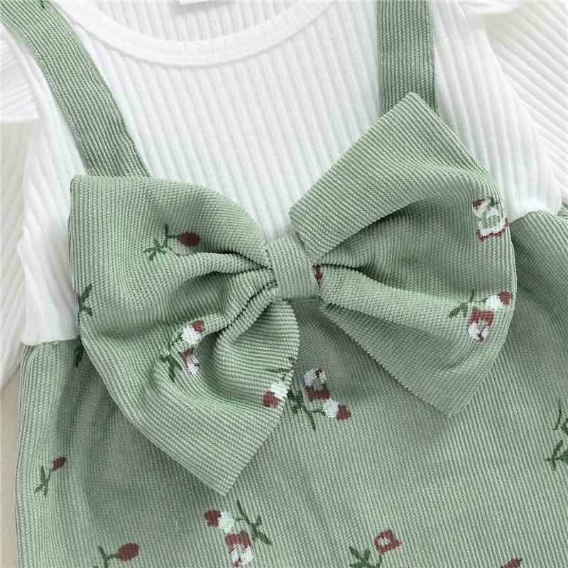 Close-up of the large decorative front bow and textured ribbed white bodice on the sage green floral corduroy baby romper.