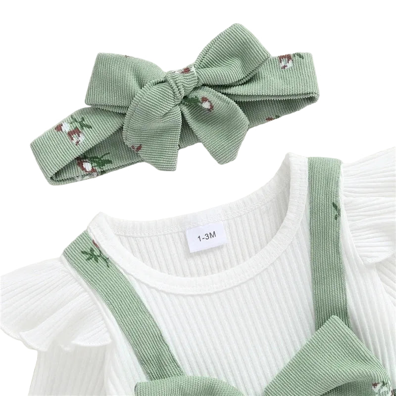 Close-up of the sage green baby romper showing the ribbed white crew neckline, delicate ruffle shoulders, corduroy suspender straps, and matching floral headband.