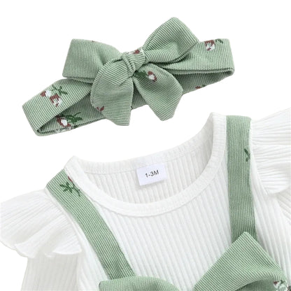 Close-up of the sage green baby romper showing the ribbed white crew neckline, delicate ruffle shoulders, corduroy suspender straps, and matching floral headband.
