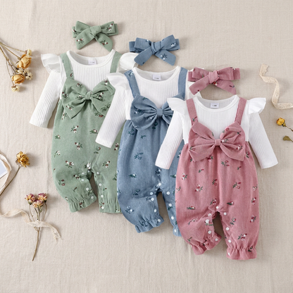 Three cottagecore floral corduroy baby overall rompers in sage green, slate blue, and dusty pink, laid flat with their matching headbands.