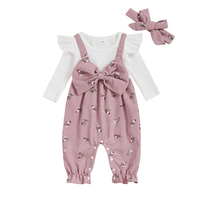 Dusty pink floral corduroy baby girl overall romper featuring an oversized bow and a matching headband on a white background.