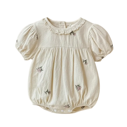 Front view of a cream baby girl bubble romper featuring short puff sleeves, a lace collar, and pink floral embroidery on a white background.