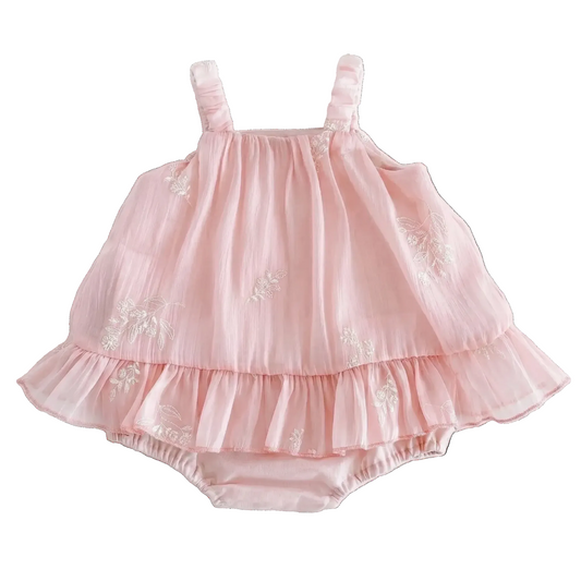 Flat lay of a soft pink baby girl princess romper dress with white floral embroidery and ruffled hem on a clean white background.