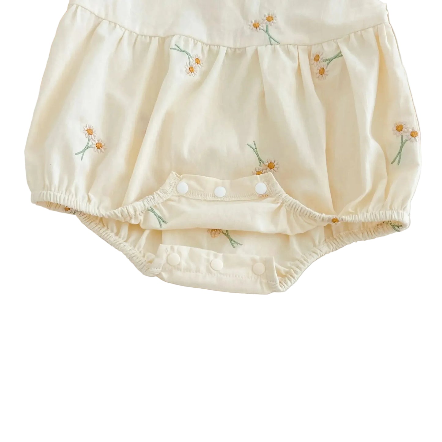 Close-up view of open bottom snap closures on cream baby girl embroidered bubble romper
