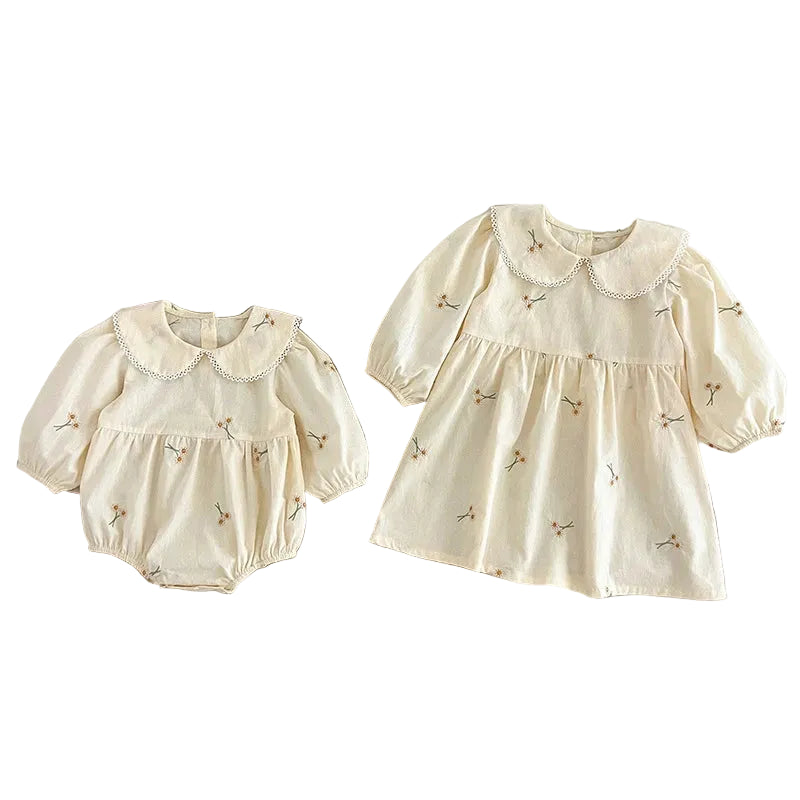 Matching set featuring cream floral embroidered baby girl romper and sister dress on white background